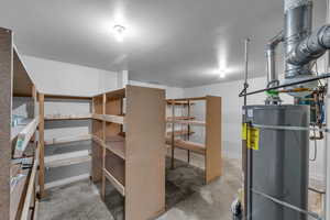 Basement featuring a textured ceiling and water heater