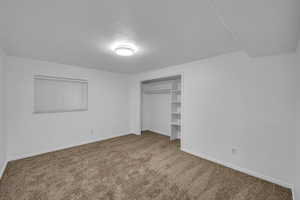 Unfurnished bedroom with carpet, a textured ceiling, and a closet