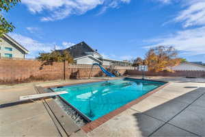 View of pool featuring a patio area, a diving board, and a water slide