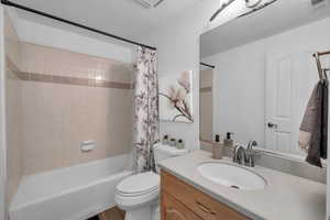 Full bathroom featuring vanity, toilet, shower / bathtub combination with curtain, and a textured ceiling