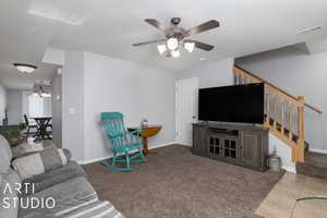 Living room with ceiling fan with notable chandelier and light carpet