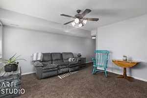 Living room featuring dark colored carpet and ceiling fan