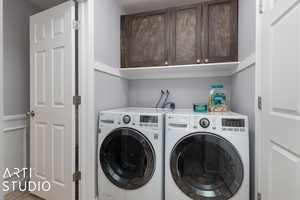 Clothes washing area featuring cabinets and separate washer and dryer