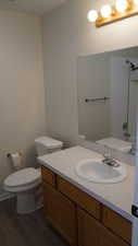 Bathroom featuring vanity, toilet, wood-type flooring, and a shower