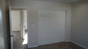 Unfurnished bedroom featuring dark carpet and a closet