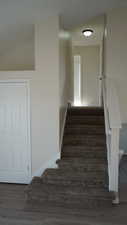 Stairway featuring wood-type flooring and vaulted ceiling