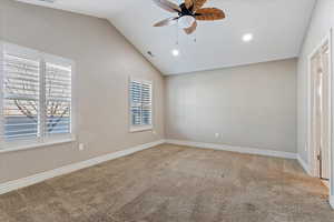 Carpeted empty room featuring vaulted ceiling, ceiling fan, and a healthy amount of sunlight