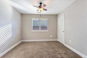 Carpeted spare room featuring ceiling fan