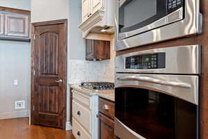 Kitchen featuring light stone countertops, appliances with stainless steel finishes, and decorative backsplash