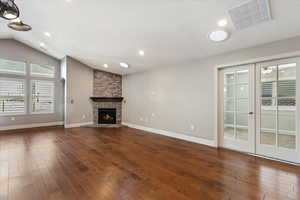 Unfurnished living room featuring a textured ceiling, a fireplace,  and vaulted ceiling