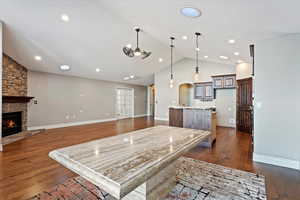 Living room with a fireplace, vaulted ceiling, and ceiling fan