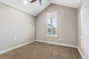 Empty room featuring carpet flooring, ceiling fan, and lofted ceiling