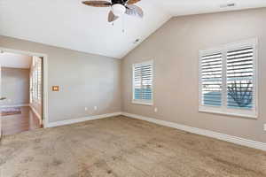 Spare room with carpet flooring, ceiling fan, and lofted ceiling