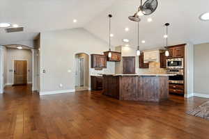 Kitchen with pendant lighting, backsplash, stainless steel appliances, and dark wood-type flooring