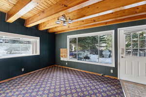 Interior space with beam ceiling, an inviting chandelier, and wood walls