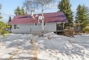 Snow covered rear of property featuring a deck