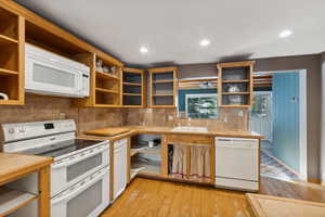 Kitchen with tasteful backsplash, sink, light hardwood / wood-style floors, and white appliances