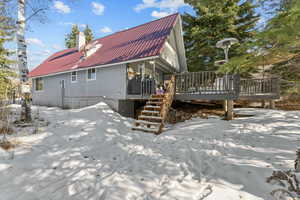 Snow covered back of property with a deck