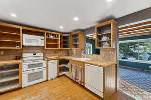 Kitchen featuring tile counters, sink, light hardwood / wood-style floors, white appliances, and decorative backsplash