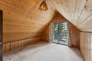 Bonus room featuring wooden walls, wooden ceiling, vaulted ceiling, and light carpet