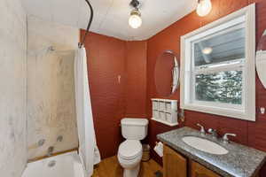 Full bathroom featuring hardwood / wood-style floors, vanity, toilet, and shower / bath combo with shower curtain