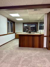 Kitchen with a paneled ceiling, kitchen peninsula, and light colored carpet