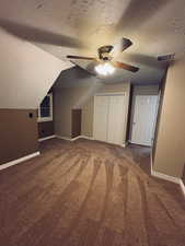 Bed room with lofted ceiling, ceiling fan, dark carpet, and a textured ceiling