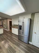 Kitchen with high end refrigerator, white cabinets, and dark wood-type flooring