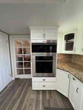 Kitchen with white cabinets, dark wood-type flooring, and dark stone countertops