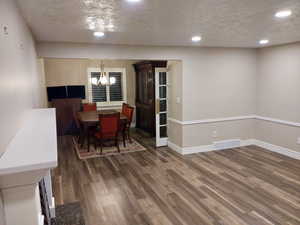 Dining room with a textured ceiling, dark hardwood / wood-style floors, and a notable chandelier