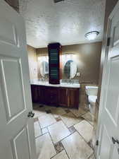 Master Bathroom with a textured ceiling, vanity, toilet, and tile walls