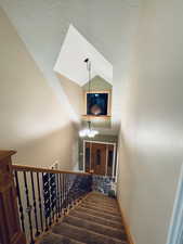 Staircase featuring a chandelier and vaulted ceiling