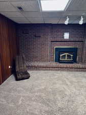 Interior space with a paneled ceiling, wood walls, and carpet floors