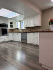 Kitchen with dishwasher, sink, dark hardwood / wood-style floors, a textured ceiling, and white cabinetry