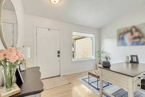 Entryway with lofted ceiling and light wood-type flooring