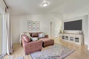 Living room with light hardwood / wood-style flooring and vaulted ceiling