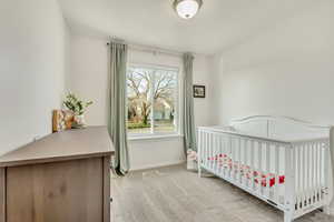 Bedroom with light colored carpet and a nursery area