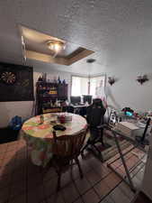 Dining space with a tray ceiling, dark tile patterned floors, and a textured ceiling