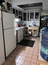 Kitchen featuring a textured ceiling, white appliances, light tile patterned floors, and sink