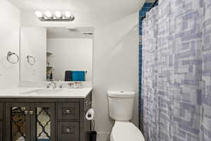 Bathroom with a shower with curtain, vanity, and toilet