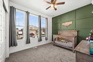 Bedroom with carpet, ceiling fan, and a nursery area