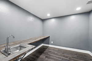 Clothes washing area with dark hardwood / wood-style flooring and sink