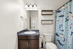 Bathroom with a shower with shower curtain, vanity, and toilet