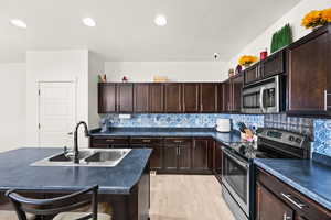 Kitchen featuring appliances with stainless steel finishes, tasteful backsplash, light hardwood / wood-style flooring, and sink