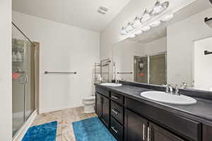 Bathroom with vanity, toilet, and a shower with shower door