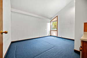 Carpeted empty room with vaulted ceiling