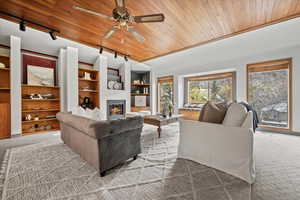 Living room featuring light carpet, crown molding, ceiling fan, and wooden ceiling