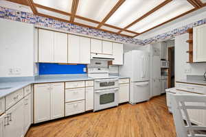 Kitchen featuring white cabinets, light hardwood / wood-style floors, and white appliances