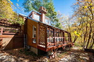 View of side of home with a wooden deck and a sunroom