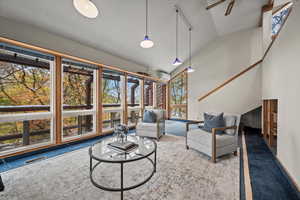 Living room with a wall mounted air conditioner, ceiling fan, carpet, and vaulted ceiling